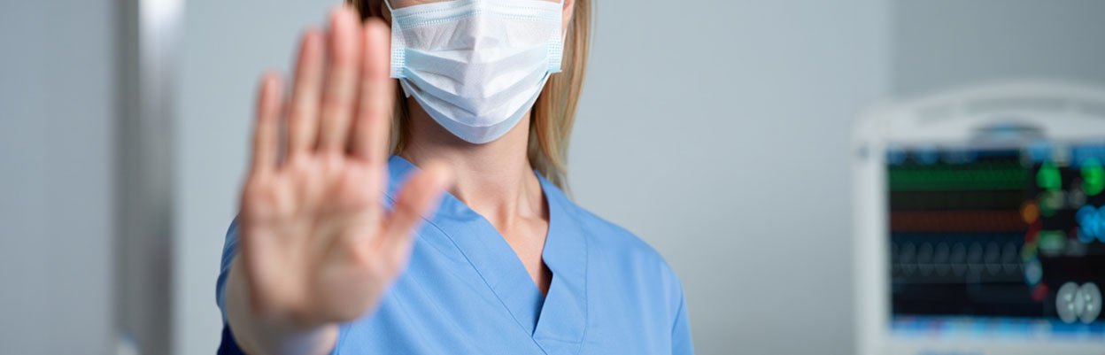 Врач в маске показывает жест остановки